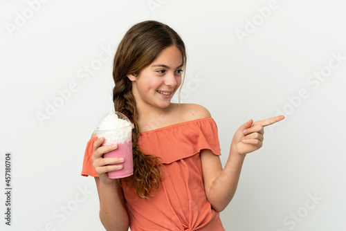 Little caucasian girl with strawberry milkshake isolated on white background pointing finger to the side and presenting a product