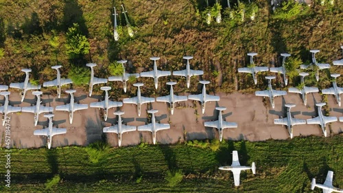 Squadron of old jet fighters used by USSR army stands near dismantled MI-8 helicopters on ground at abandoned air base upper view