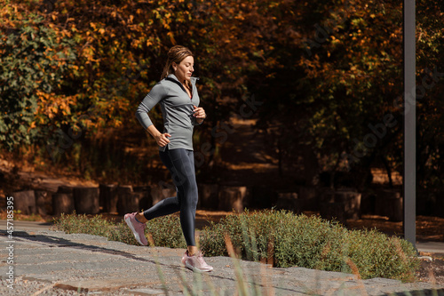 Running fitness women in autumn city park. Sport activity in fall season.