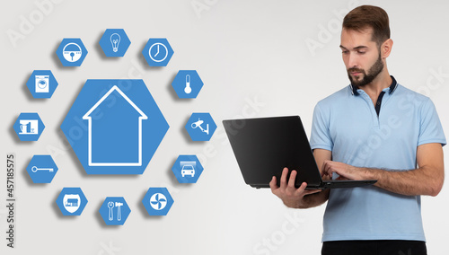 Software engineer is developing smart house system. Man next to IOT home icons. programmer with laptop creates software. Egineer configures IOT home. IOT home system sync. Light smart house concept photo