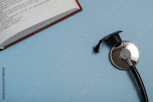 medical education. stethoscope, book and graduate hat. medical concept on blue background. graduate