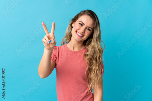 Young Brazilian woman isolated on blue background smiling and showing victory sign