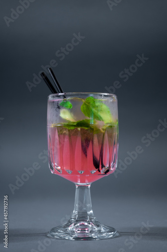 refreshing pink lemonade with mint or rose cocktail in glass on grey background