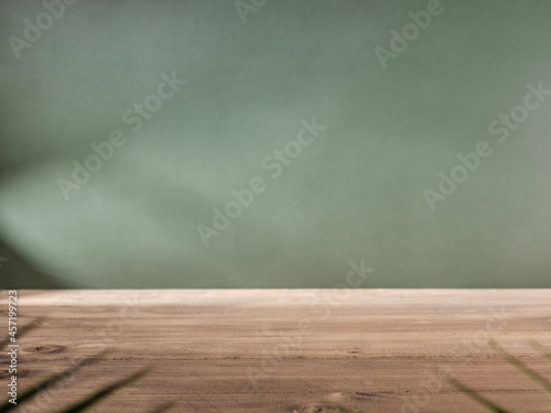 Wooden table top on green wall background