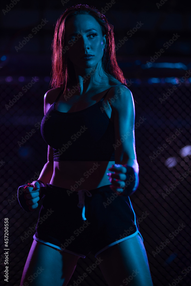 Boxing. Sport concept. Girl fighter on combat without rules in a cage oktobox. Neon photo