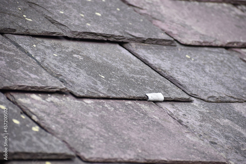 Close up of an old slate hook repair holding a Welsh slate tile in place.