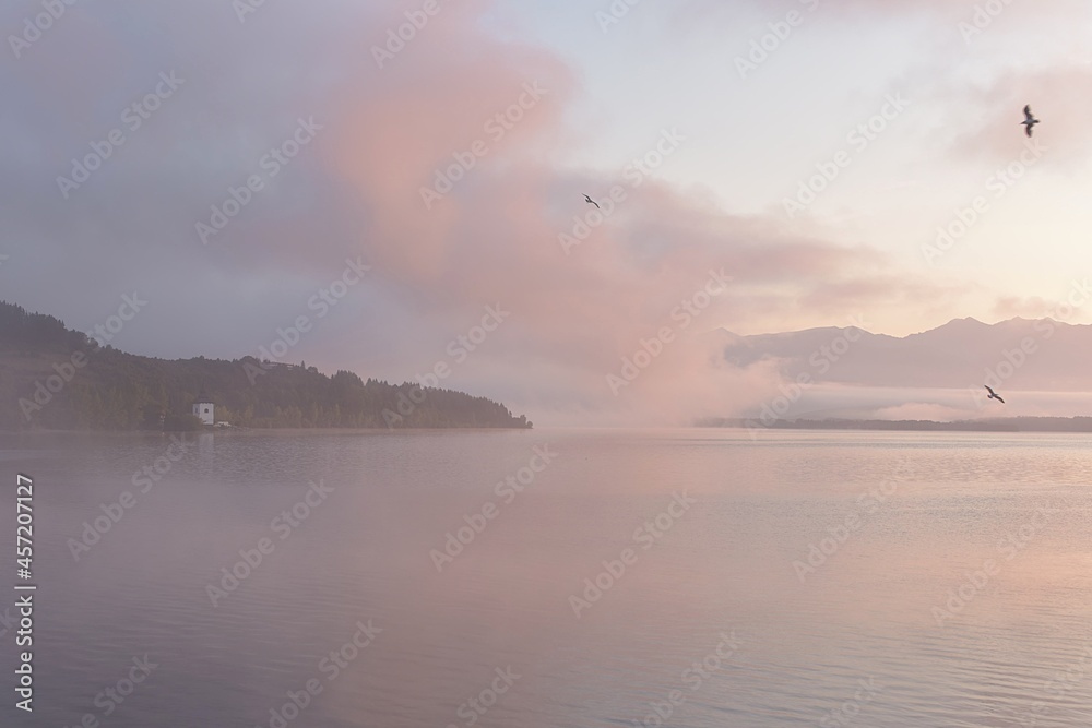 sunrise over the reservoir. A pink mist in the morning mist hovers over the water.