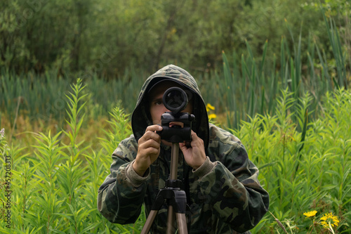 man wildlife researcher makes observations in the wild with a spotting scope photo