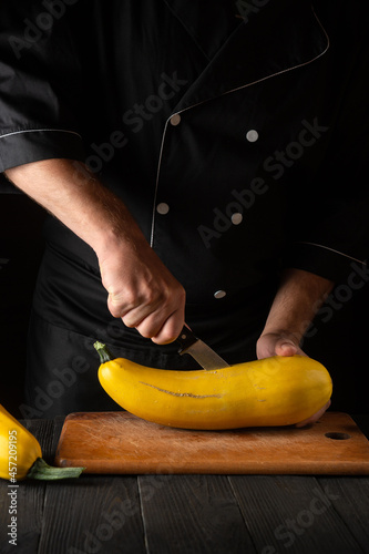 Professional chef cuts ripe yellow marrow with a knife. Fried zucchini is a great diet for breakfast or lunch. Work environment on the kitchen table of the restaurant.