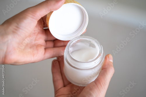 Female hands hold a jar of moisturizing cream.