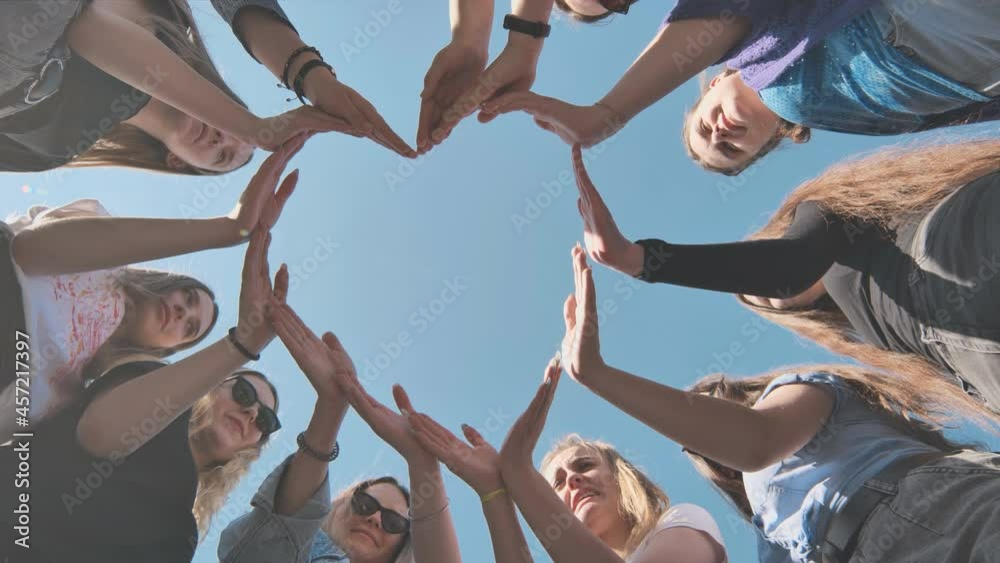 Cheerful girlfriends make a heart shape out of their hands.