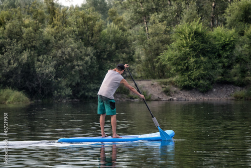 A man sup surfing paddling on a boat on the river in summer. © Marina