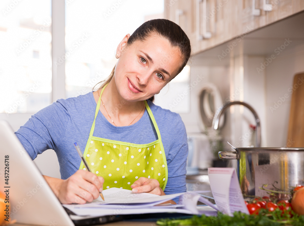 Smiling young woman reading recipe in the kitchen. High quality photo