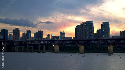 Seoul Skyline Silhouette - Traffic and Subway Train Crossing At Cheongdam Bridge Over Han River With People Kayaking During Sunset In Seoul, South Korea. photo