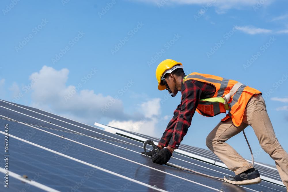 Solar panel technician with drill installing solar panels on roof at solar panel field,Environmental protection,Alternative clean green energy concept. Solar panel technician with drill installing solar panels on roof at solar panel field,Environmental protection,Alternative clean green energy concept.