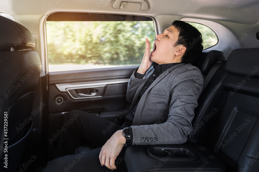 sleepy business man yawning while sitting in the back seat of car sleepy business man yawning while sitting in the back seat of car