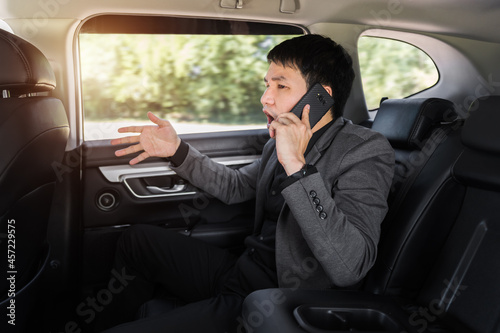 stressed business man talking problem on a mobile phone while sitting in the back seat of car