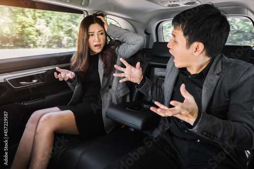 two stressed business man and woman arguing while sitting at the back seat of car