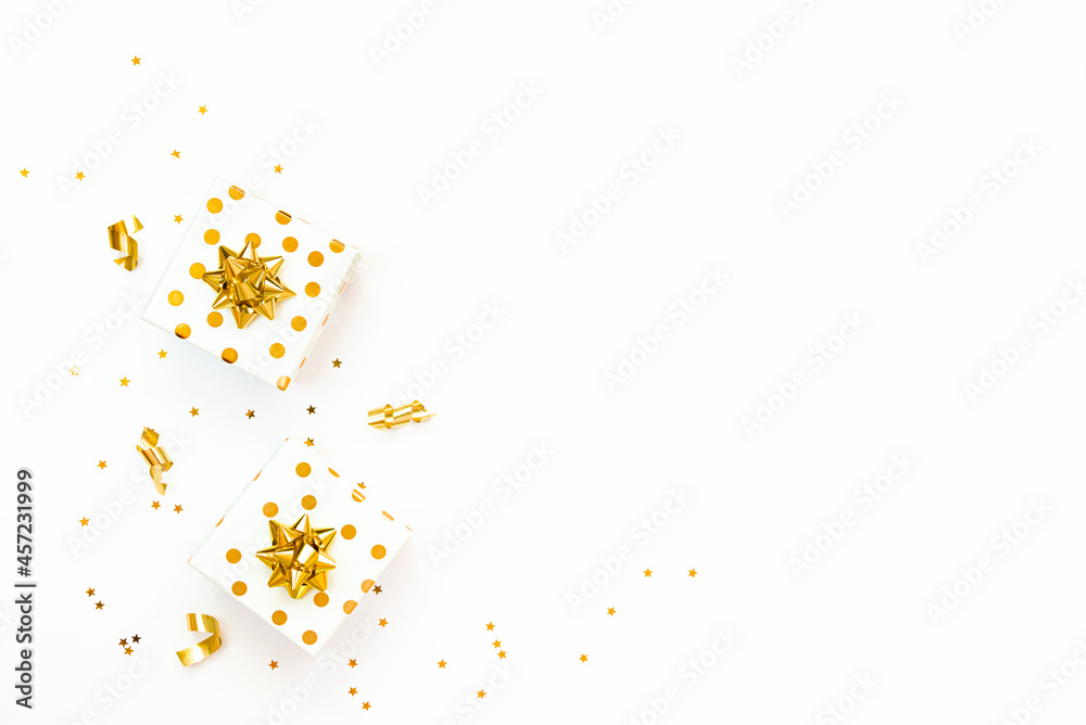 Top view of golden dotted gift boxes and star shaped golden confetti on a white background. Copy space.