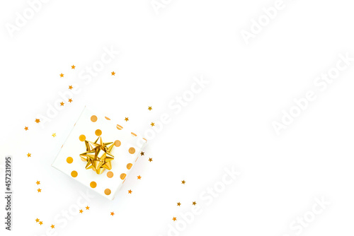 Obraz na płótnie Top view of a golden dotted gift box and star shaped golden confetti on a white background. Copy space. w salonie