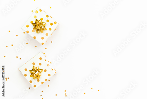 Obraz na płótnie Top view of golden dotted gift boxes and star shaped golden confetti on a white background. Copy space. w salonie