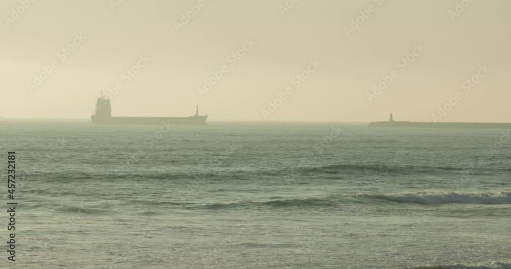 Freight Barge Sailing Across The Sea Obscure By Morning Fog In Figueira da Foz, Portugal. - wide shot Freight Barge Sailing Across The Sea Obscure By Morning Fog In Figueira da Foz, Portugal. - wide shot