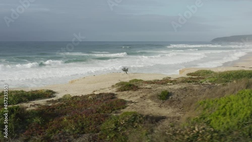 Lonely traveler sits in a chair on the coastal hill, enjoying pristine natural beauty of the Atlantic Ocean. Drone footage of a peaceful, undiscovered gem of Portugal. High quality 4k footage
