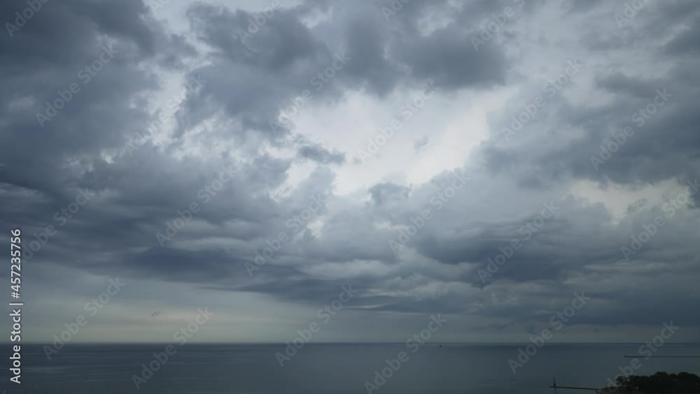 Aerial panning view of dramatic undulating storm clouds rolling across the sky over the water of Lake Michigan part of a large weather front with rain and thunderstorms seen in the distance.