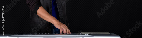 Closeup musician's hand playing on a music keyboard player in front of black soundproofing walls. Musician producing music in professional recording studio.