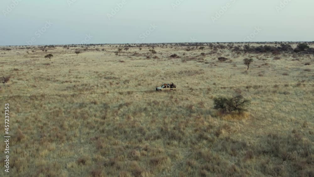 Namibian Desolate Landscape With Traveling Safari Vehicle In Nature Parks Of South Africa. Aerial Namibian Desolate Landscape With Traveling Safari Vehicle In Nature Parks Of South Africa. Aerial
