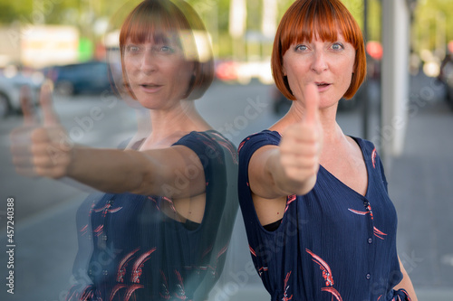 Attractive enthusiastic redhead woman giving a thumbs up