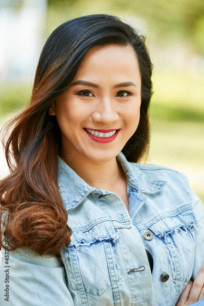 Portrait of happy positive young Vietnamese brunette standing outdoors on sunny summer day Portrait of happy positive young Vietnamese brunette standing outdoors on sunny summer day