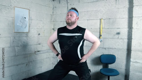 Funny overweight man doing hip workout exersises in a garage. photo