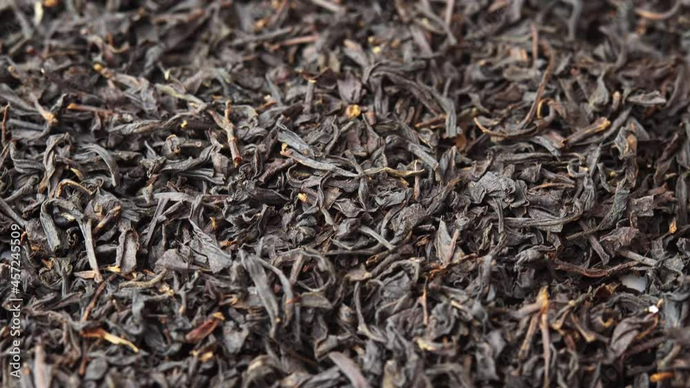 Black loose leaf tea spinning close up on plate, background for a cafe or restaurant black tea, tea advertising Black loose leaf tea spinning close up on plate, background for a cafe or restaurant black tea, tea advertising