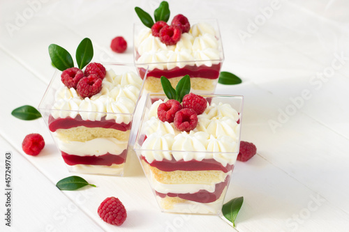 Fototapeta Naklejka Na Ścianę i Meble -  Dessert with raspberry , delicious  dessert with fresh berries., portion dessert in a clear plastic cups. White wooden board, healthy eating , healthy dessert, red berries cake