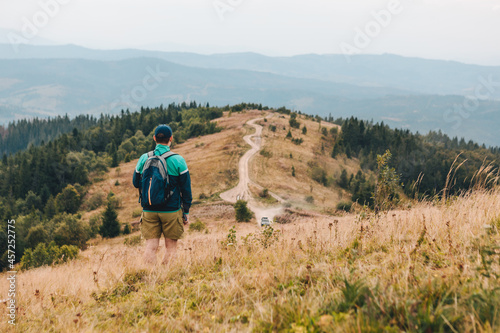 man with backpack hiking by autumn mountains