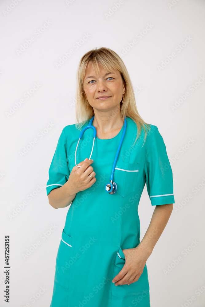 Portrait of pretty blonde doctor with stethoscope in turquoise medical uniform . Modern medical equipment. Medicine and health. Right way of life. Medicine and insurance.