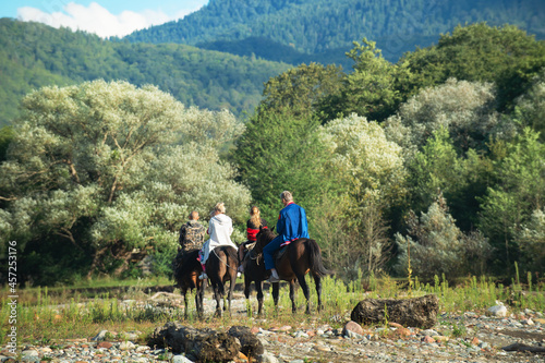 Tableau sur toile A group of people from children and adults ride horses in the mountains