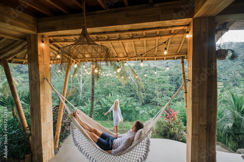 A couple in love sits in a villa in Bali and admires the view of the rice fields
