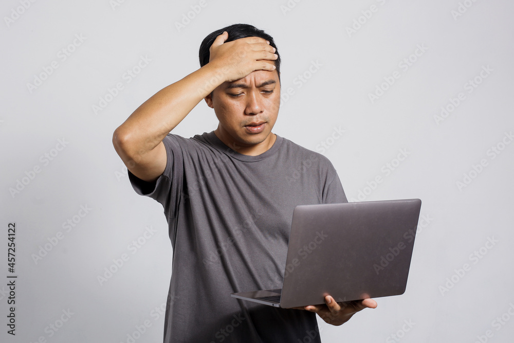 Sad unhappy Asian man get bad news from a laptop Sad unhappy Asian man get bad news from a laptop