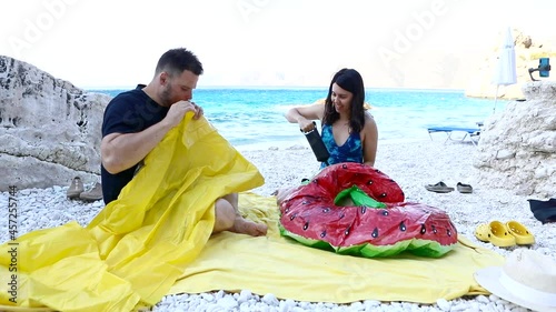 couple having fun inflate inflatable mattress at sea beach