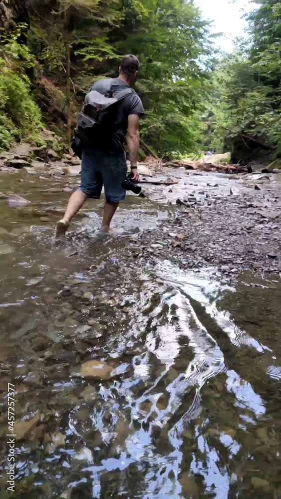 man backpacker walking to waterfall man backpacker walking to waterfall