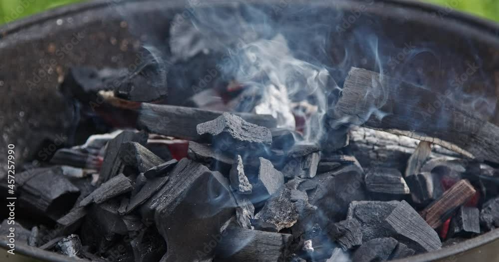 Fire and smoke cloud from burning charcoal grill. Flames and smoke - food preparation. Grilling shashlik outside on a barbecue grill. Outdoor grill party in the summer season.