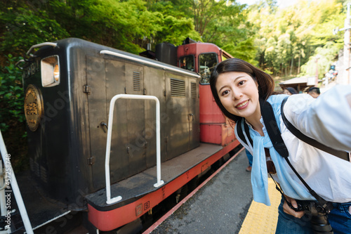 happy asian woman is taking a self portrait with the locomotive of sagano romantic train at the station on a sunny day in Arashiyama Kyoto, japan photo