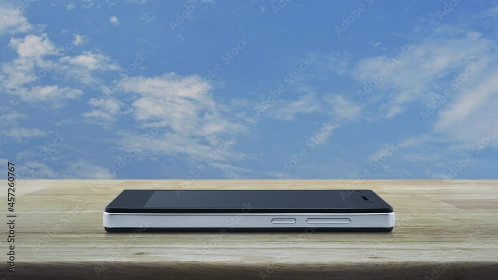 Play button flat icon on modern smart mobile phone screen on wooden table over blue sky with white clouds, Business music online concept Play button flat icon on modern smart mobile phone screen on wooden table over blue sky with white clouds, Business music online concept
