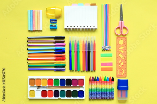 Painting supplies on a colored background. Set of first grader on a yellow background. Office supplies in a layout on a yellow paper background. Flat layout