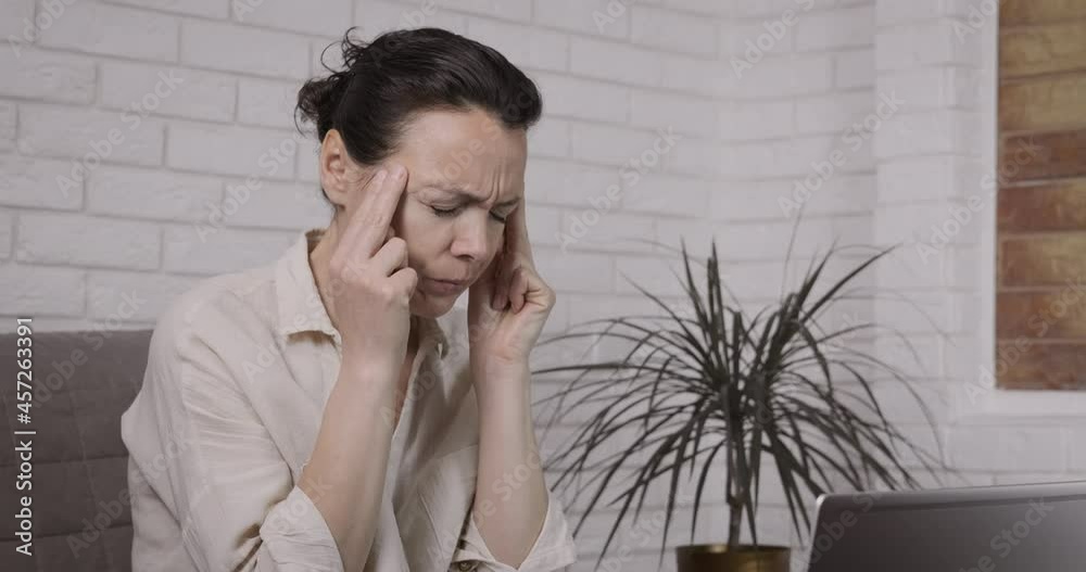 Freelancer with headache. An exhausted frustrated freelancer stop for a while to work on her notebook at home office. Freelancer with headache. An exhausted frustrated freelancer stop for a while to work on her notebook at home office.