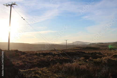 A power line with some mountains in the background during golden hour