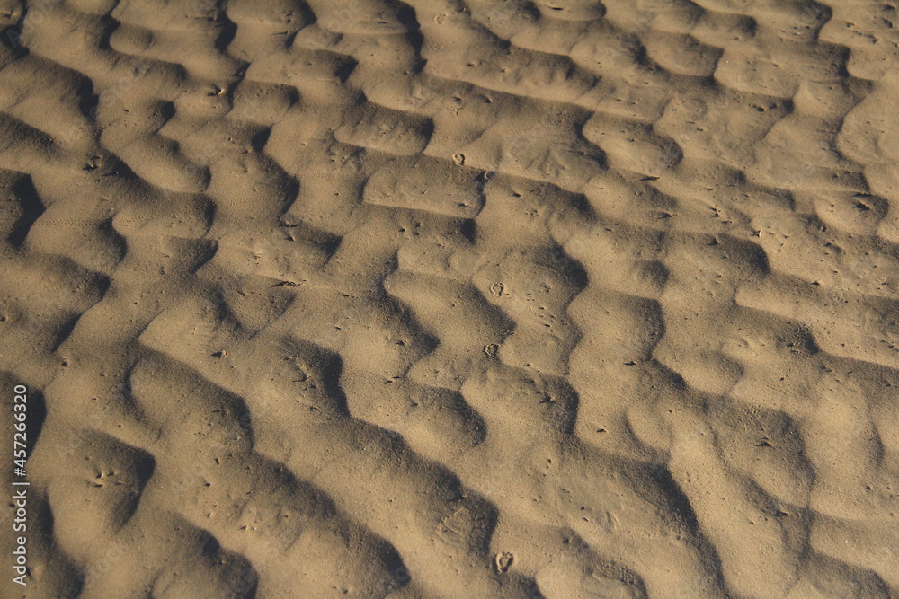 Obraz premium Traces of waves in the sand, close-up, wavy pattern with a beautiful shadow, summer, sunny