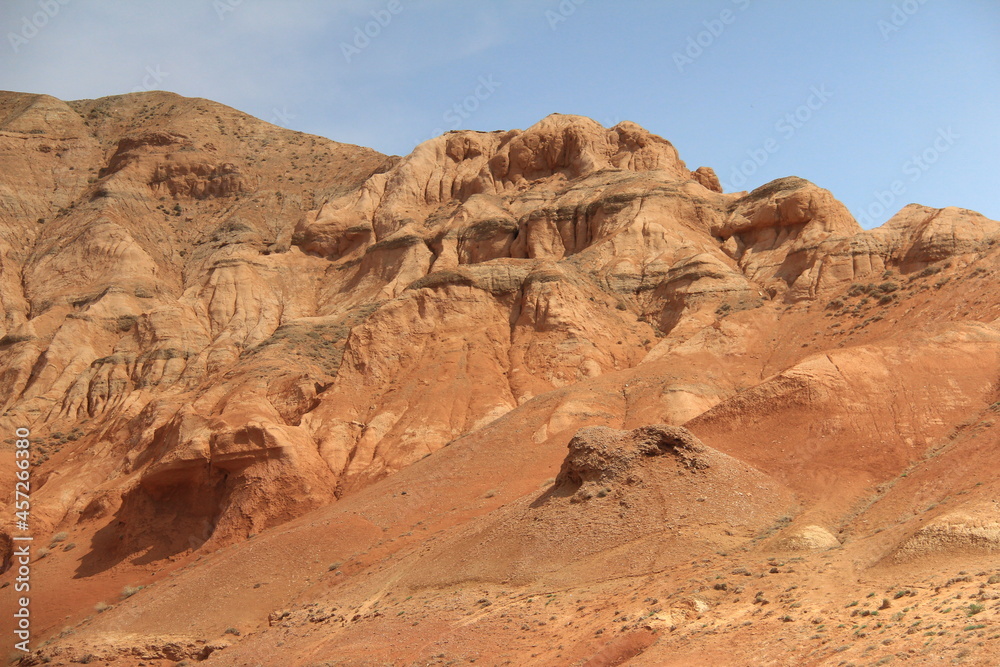 Beautiful red sandy-clay mountains Boguty with an unusual relief in summer against a clear sky, Altyn-Emel national park, summer, sunny